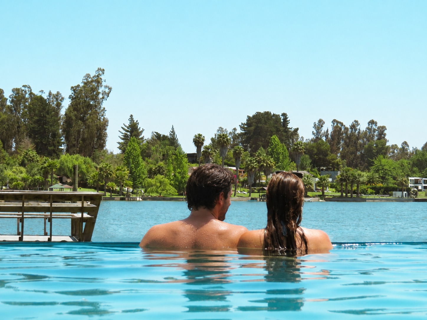 Pareja en la piscina mirando juntos hacia el lago
